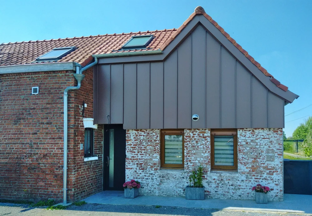 Maison individuelle en brique rouge avec volets battants gris, toiture en tuiles mécaniques terre cuite