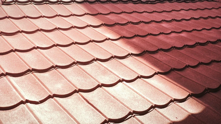 Chantier de construction extérieur avec ouvriers installant des tuiles terre cuite sur toiture en pente