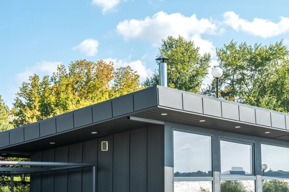 Trois ouvriers installent une couverture sur une charpente en bois