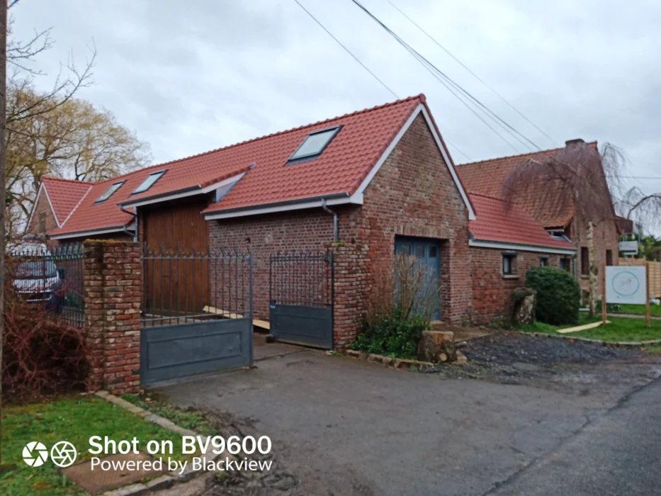 Maison moderne avec extension contemporaine à bardage métallique gris anthracite sur soubassement en briques anciennes patinées