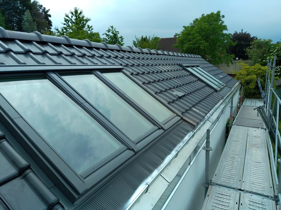Maison moderne avec extension contemporaine à bardage métallique gris anthracite sur soubassement en briques anciennes patinées