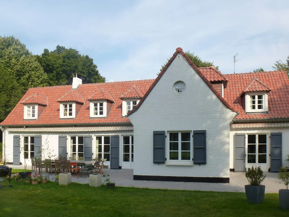 Maison moderne avec extension contemporaine à bardage métallique gris anthracite sur soubassement en briques anciennes patinées
