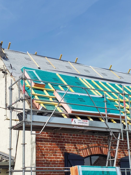 Ouvrier en construction travaillant sur une toiture ext&eacute;rieure, installant des &eacute;l&eacute;ments de couverture